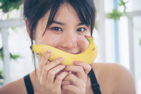 Banana Healthy eating young woman workout holding organic banana fruit healthy lifestyle. Wellness Asian women use yellow banana smile face look at camera. Beautiful healthcare nutrition lifestyleの写真素材