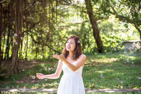 Portrait Asian Woman relaxing in green park. Happy Relax asian woman smiling face at outdoors garden. Young women enjoy nature freedom lifestyle. Greenery wellbeing outside beauty in nature.の写真素材