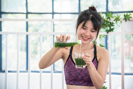 Women hands holding smoothie detox green juice fresh fruit cool drinking. Asian women smile laugh drinking vegan vegetable cool wellness beverage. Female pouring celery juice drink cocktail glassの写真素材