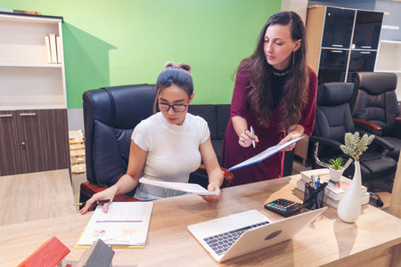 Diversity Two Businesswoman working together in office desk. Two cuacasian asian women look at financial report document as partner teamwork. Team leader coworker brainstorming executive entrepreneurの写真素材