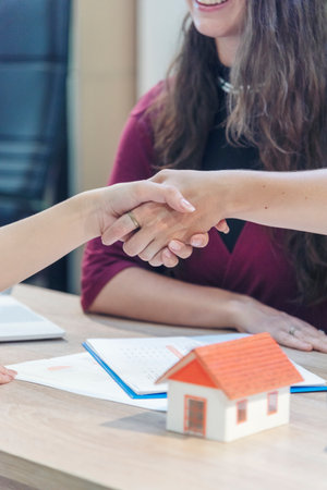 Close up Businesswoman shakes hands customer dealing real estate house agent signing contract. Diversity women agent hands office desk. Crop Women handshake sign on insurance mortgage sale documentの写真素材
