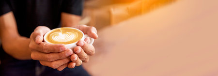 Banner Coffee barista pour espresso shot and make latte art hot coffee cup. Cappuccino with milk in italian coffee shop cafe. Banner Close up hands of barista make brown latte art with copy spaceの写真素材