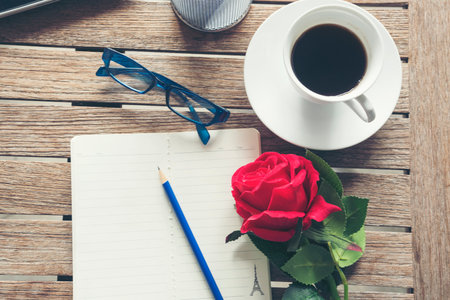 Top view office desk smart tablet document paper, coffee cup roses on wood table with copy space. Tabletop notebook office empty blank white paper pen coffee cup to display workspace wood backgroundの写真素材
