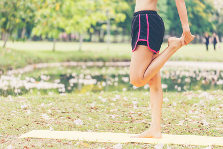 Portrait Woman stretching legs arm body exercise home fitness in green park. Healthy women workout on floor in morning. Beautiful Female in sportswear healthy lifestyle. Young girl practice stretchの写真素材
