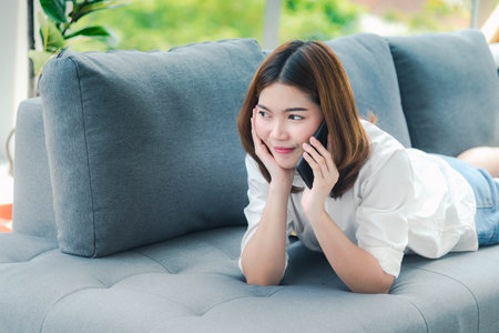 Smiling face asian woman holding smartphone with E-commerce Shopping online website Reading Online Article, Blog, vlog. Young Woman hands holding phone technology lifestyle. Woman using smart phone.の写真素材