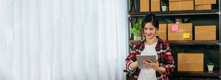 Banner Online seller Close up hands Young asian woman typing laptop keyboard checking online order on stock delivery package. Asian woman startup small business at home office with copy spaceの写真素材