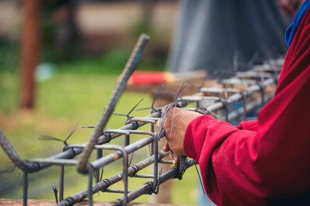 Construction Worker hands using pincer pliers iron wire. Outdoor Worker using wire bending pliers, construction work. Men hands bending cutting steel wire fences bar reinforcement of concrete workの写真素材