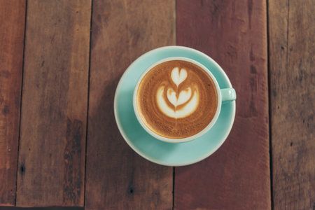 Latte art coffee cup with milk on wooden table. Espresso shot make latte art hot coffee cup. Cappuccino with milk in italian coffee shop cafe. Brown hot caffeine beverage in cafeteria with copy spaceの写真素材