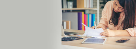 Banner woman working office desk reading financial report finance chart graph on table. Wide tax audit woman hands working paperwork office. Banner Businesswoman Audit financial with copy spaceの写真素材