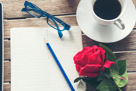 Top view office desk smart tablet document paper, coffee cup roses on wood table with copy space. Tabletop notebook office empty blank white paper pen coffee cup to display workspace wood backgroundの写真素材
