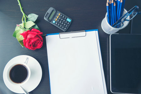 Top view office desk smart tablet document paper, coffee cup roses on wood table with copy space. Tabletop notebook office empty blank white paper pen coffee cup to display workspace wood backgroundの写真素材