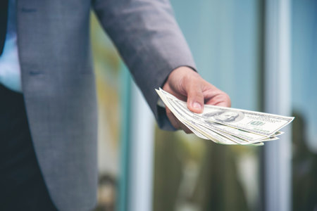 Hand holding money dollar bank note in wallet give financial payment. Man hands showing spread 100 dollar exchange cash in wallet. Saving Businessman counting money banknote concept.の写真素材