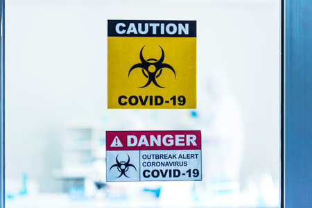 Biohazard disease alert corona outbreak sign on glass wall laboratory science center. Medical care clinic with hazard alert sign. Medical Healthcare concept.の写真素材