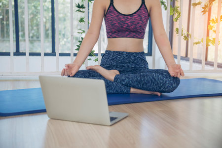 Sport Women home fitness workout exercise in living room look at laptop online trainer. Young woman using laptop on floor in sportswear arms stretching body weight traning healthy lifestyle conceptの写真素材