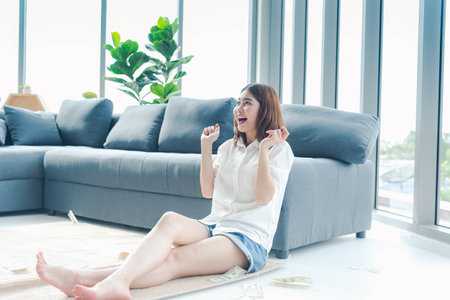 Happy young asian woman holding dollar money and throw in the air celebrate happiness dance wealth lottery money rain drop. Winner Success business woman throw cash flow Happy money smiling faceの写真素材