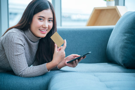 Smiling face asian woman holding smartphone with E-commerce Shopping online website Reading Online Article, Blog, vlog. Young Woman hands holding phone technology lifestyle. Woman using smart phone.の写真素材