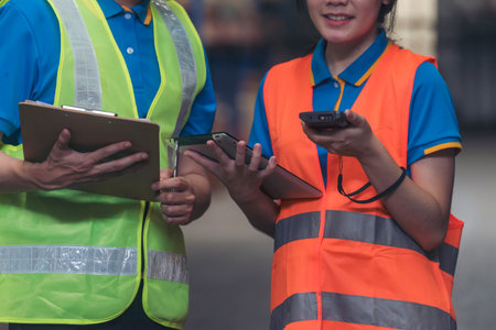 Warehouse management team check stock inventory. Asian men women worker use bar code scaner scan goods shelf writing checklist on clipboard. Teamwork logistics staff counting products store inventoryの写真素材