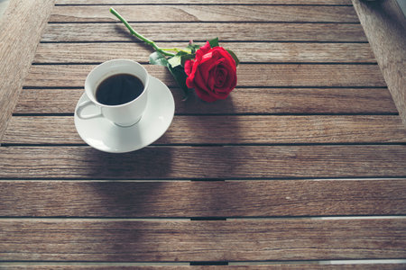 Tabletop black coffee cup red rose on wood table background with empty copy space. Espresso shot caffeine hot coffee cup in cafe. Top view Black caffeine dark beverage in cafeteria with copy spaceの写真素材