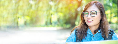 Banner Portrait Asian Woman relaxing in green park. Happy Relax asian woman smiling face at outdoors garden. Women enjoy nature freedom lifestyle. Greenery wellbeing outside in nature with copy spaceの写真素材