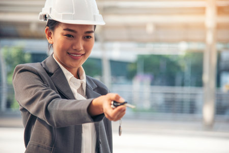 Civil women engineer wear safety white hard hat Hands using remote control car key. Close up hands of young woman showing key of new car. Businesswoman holding car rental key vehicle dealership.の写真素材