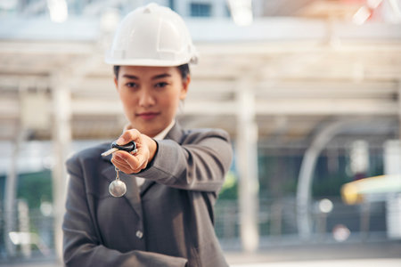 Civil women engineer wear safety white hard hat Hands using remote control car key. Close up hands of young woman showing key of new car. Businesswoman holding car rental key vehicle dealership.の写真素材