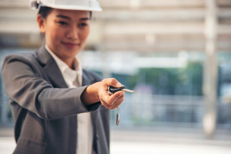 Civil women engineer wear safety white hard hat Hands using remote control car key. Close up hands of young woman showing key of new car. Businesswoman holding car rental key vehicle dealership.の写真素材