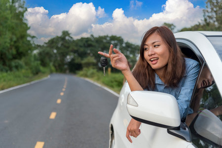 Happy asian women drive new car. Women Hand give remote control car key to man rental car service. Close up hands young woman showing new car key. Women driver giving car rental service smiling faceの写真素材