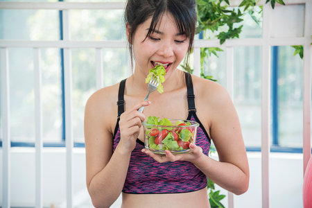 Healthy woman workout holding organic salad bowl healthy lifestyle. Wellness Asian women dressing organic green salad tomato vegetable dish. Beautiful girl healthcare vegan wellness lifestyle conceptの写真素材