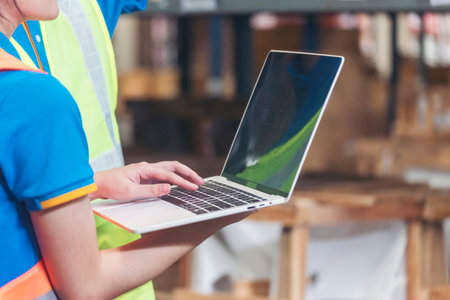 Warehouse management team using computer laptop check stock inventory. Asian men women worker use...