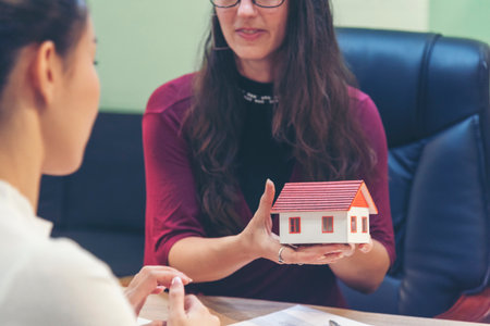 Team diversity women selling house real estate agent at office desk. Women working home insurance mortgage sale apartment realtor dealership. Businesswoman real estate house agent discuss to customerの写真素材