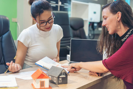 Team diversity women selling house real estate agent at office desk. Women working home insurance mortgage sale apartment realtor dealership. Businesswoman real estate house agent discuss to customerの写真素材