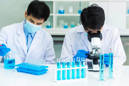 Scientist man look into Microscope research in science laboratory. Asian scientist looking equipment...