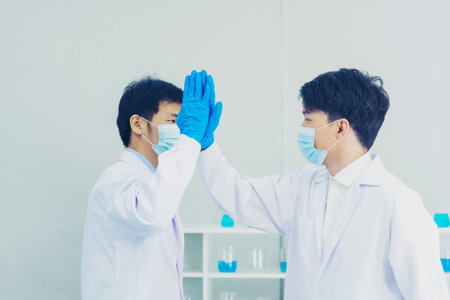 Two asian scientist men team high five partner shake hands together. Science Men research chemistry science experiment. Two men biotech coworker success greeting in laboratory. Teamwork successfulの写真素材