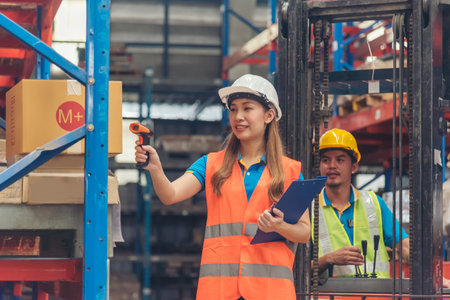 Warehouse management team use bar code scaner scan goods shelf writing checklist on clipboard. Asian men women worker check stock inventory. Teamwork logistics staff counting products store inventoryの写真素材