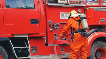 Fireman prepare equipment at fire engine truck. Man hand connect water tube with fire truck fighting...