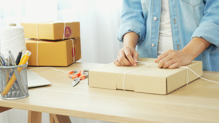 Fashion designer Women packing box on table checking goods quality package. Asian women startup small business at home office desk pack fashion design clothing. Asian woman packing startup businessの写真素材
