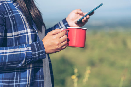 Close up Woman hand holding black coffee cup in green garden cafe. Hands of businesswoman love drinking hot coffee. business women with black coffee or hot chocolate in coffee shop. Caffeine drinkingの写真素材