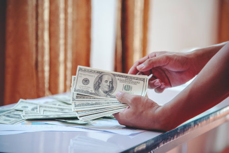 Hand holding loan money dollar bank note give financial payment. Man hands showing spread 100 dollar exchange cash payout. Saving Businessman counting money banknote concept.の写真素材
