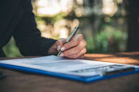 Woman hands writing empty notebook planing meeting agenda on wooden table. Close up women hands using pen drinking coffee cup planning office paper. Female hand holding pen note Personal Organizerの写真素材