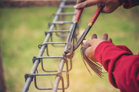 Construction Worker hands using pincer pliers iron wire. Outdoor Worker using wire bending pliers, construction work. Men hands bending cutting steel wire fences bar reinforcement of concrete workの写真素材