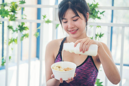 Asian women smile laugh look at camera health care home fitness lifestyle. Beautiful female drinking fresh milk. Women hands holding white glass of milk pouring from bottleの写真素材