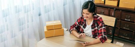 Banner Online seller Close up hands Young asian woman typing laptop keyboard checking online order on stock delivery package. Asian woman startup small business at home office with copy spaceの写真素材
