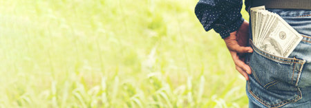 Banner Backside Businessman spreading 100 dollar banknote back jeans pocket. Hand holding money dollar bank note. Banner Man hands spread 100 dollar exchange cash with copy space.の写真素材