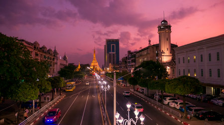 Streets of downtown Yangon Myanmar road to Sule Gold Pagoda sunset with traffic jam and modern city center. Buddhist sacred worship transport long exposure car light on street famous holy night townの写真素材