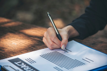 Woman hands writing empty notebook planing meeting agenda on wooden table. Close up women hands...