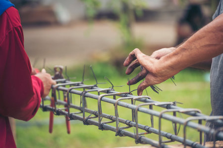 Construction Worker hands using pincer pliers iron wire. Outdoor Worker using wire bending pliers, construction work. Men hands bending cutting steel wire fences bar reinforcement of concrete workの写真素材