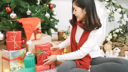 Close up woman hands wrap present gift in cozy living room. Woman wrapping christmas gift box under...