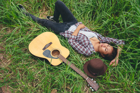 Young women playing acoustic guitar outdoor in green park. Woman person playing acoustic guitar...