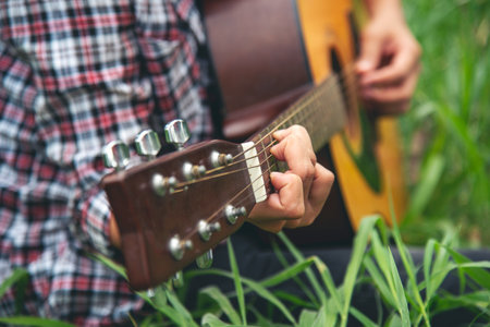 Young women playing acoustic guitar outdoor in green park. Woman person playing acoustic guitar...