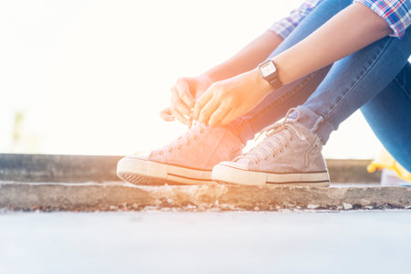 sneaker shoes young woman traveler sit down on summer park. Focus on sneaker shoes and jeans on pathway in forest park. active activity vacation on hike mountain walking way. Young traveler conceptの写真素材